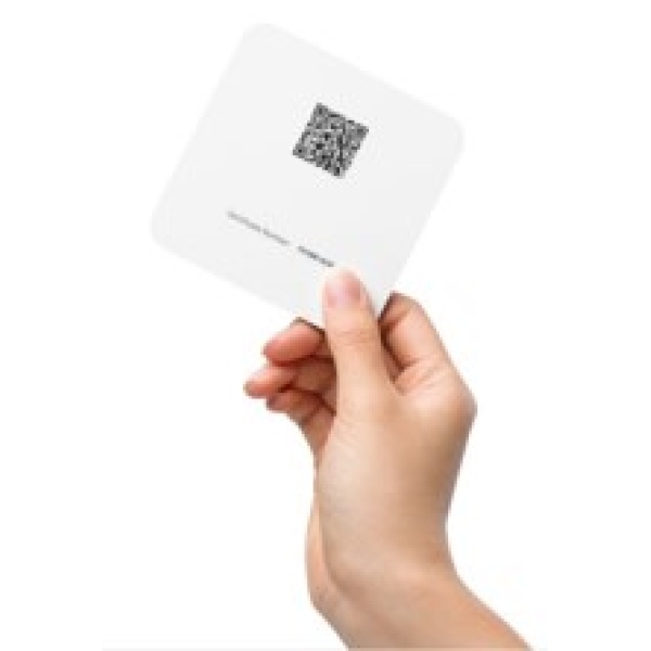 A person holding up a square card with a qr code on it.